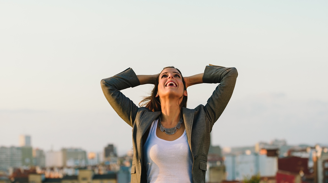 Successful young businesswoman after business or job achievement towards city background. Professional joyful woman outside.